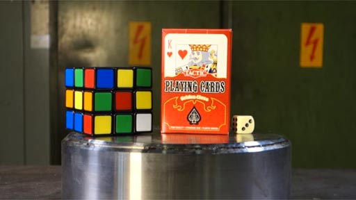 Baraja, cubo de Rubik y dado en prensa hidrulica